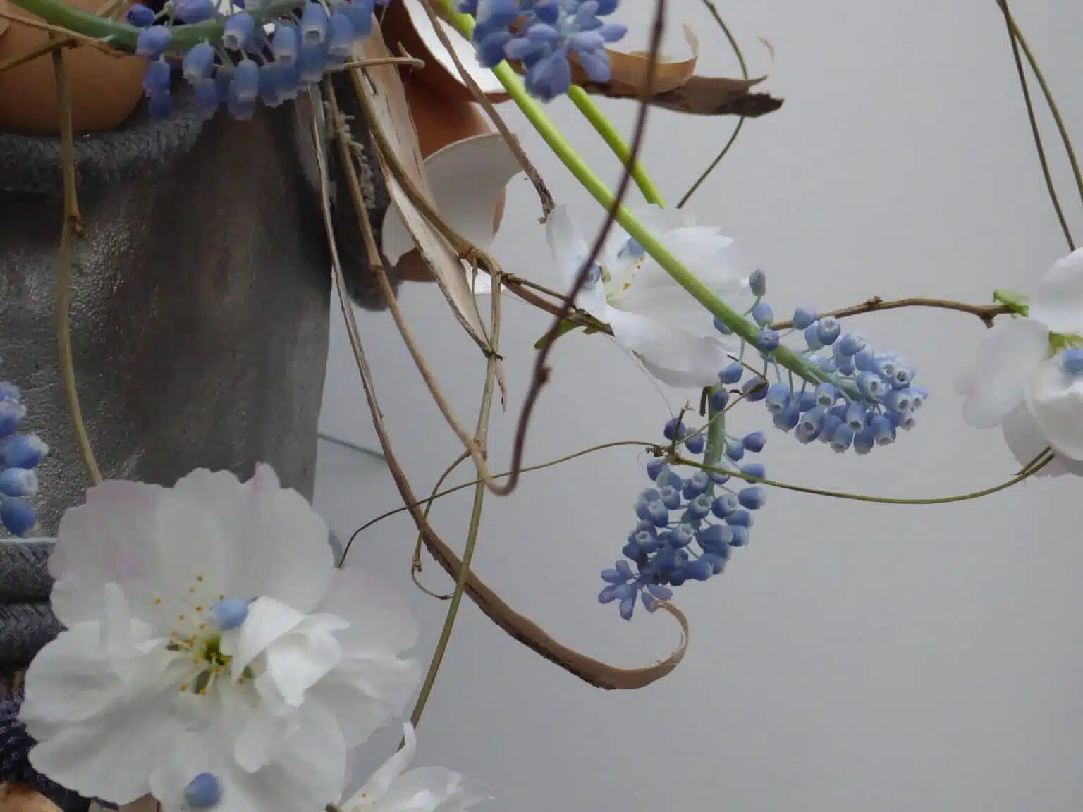 Composition florale de Pâques avec fleurs blanches, muscaris bleus et éléments naturels, création de l’atelier Yann-H2o, fleuriste Paris 11