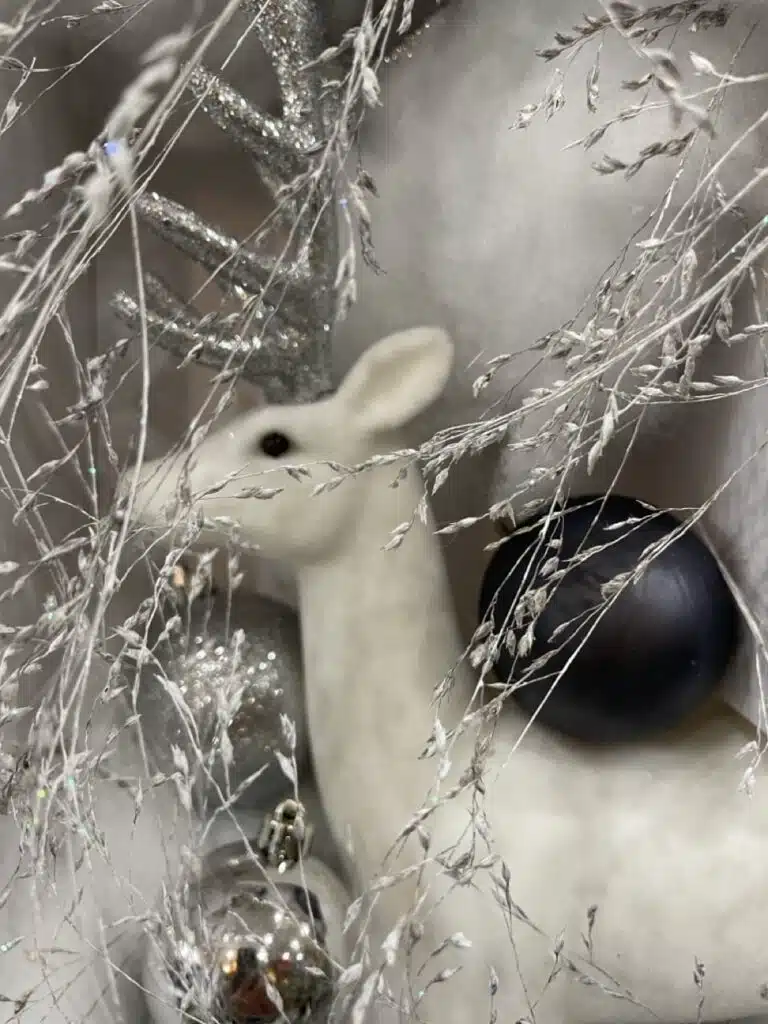 Détail d’une décoration hivernale montrant un animal décoratif blanc entouré de fines branches argentées et d’ornements bleus et argent, exprimant la douceur, le calme et la poésie des vœux 2026 du fleuriste Yann-h2o.