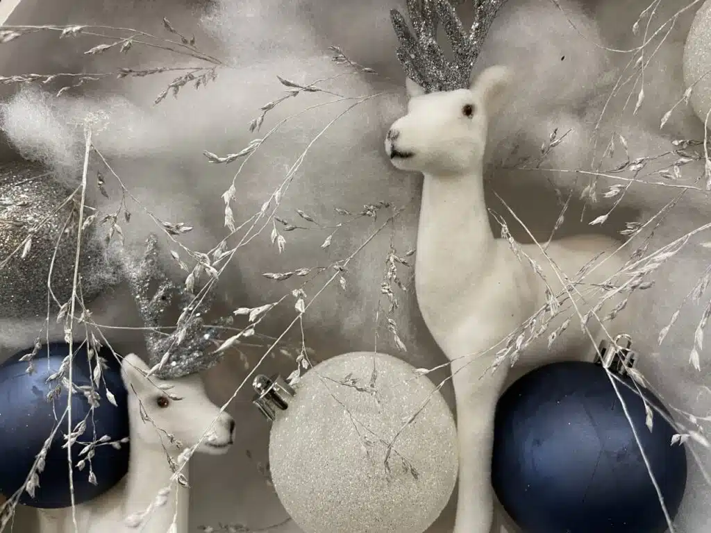 Vue sur une décoration hivernale avec des animaux décoratifs blancs, des ornements bleus et argentés et des branches délicates, évoquant la tendresse, la poésie et l’esprit des vœux 2026 du fleuriste Yann-h2o.
