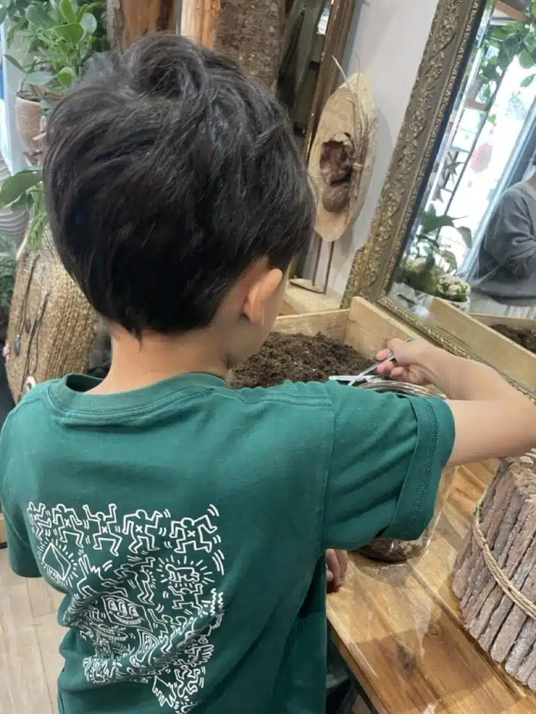 Enfant participant à un atelier terrarium lors d’un atelier floral encadré par le fleuriste Yann-H2o à Paris 11