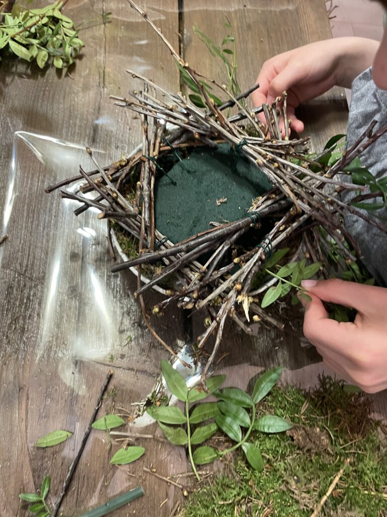 Création d’une couronne végétale en branches naturelles et feuillages lors d’un atelier floral chez Yann-H2o artisan fleuriste à Paris 11
