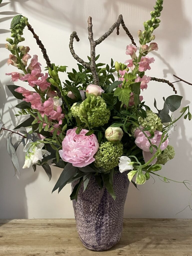 Grande composition florale réalisée par Yann Artisan Fleuriste à Paris 11, composée de pivoines françaises de saison, mufliers roses, viburnum et fleurs fraîches printanières avec livraison dans tout Paris.