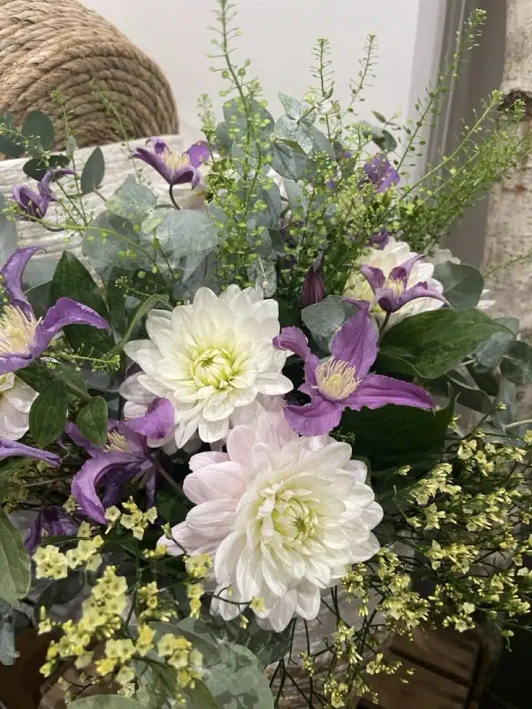 Arrangement floral composé de dahlias blancs, de clématites violettes, de limonium, d'eucalyptus et de feuillages de saison, créé par Yann-H2o, artisan fleuriste à Paris 11.