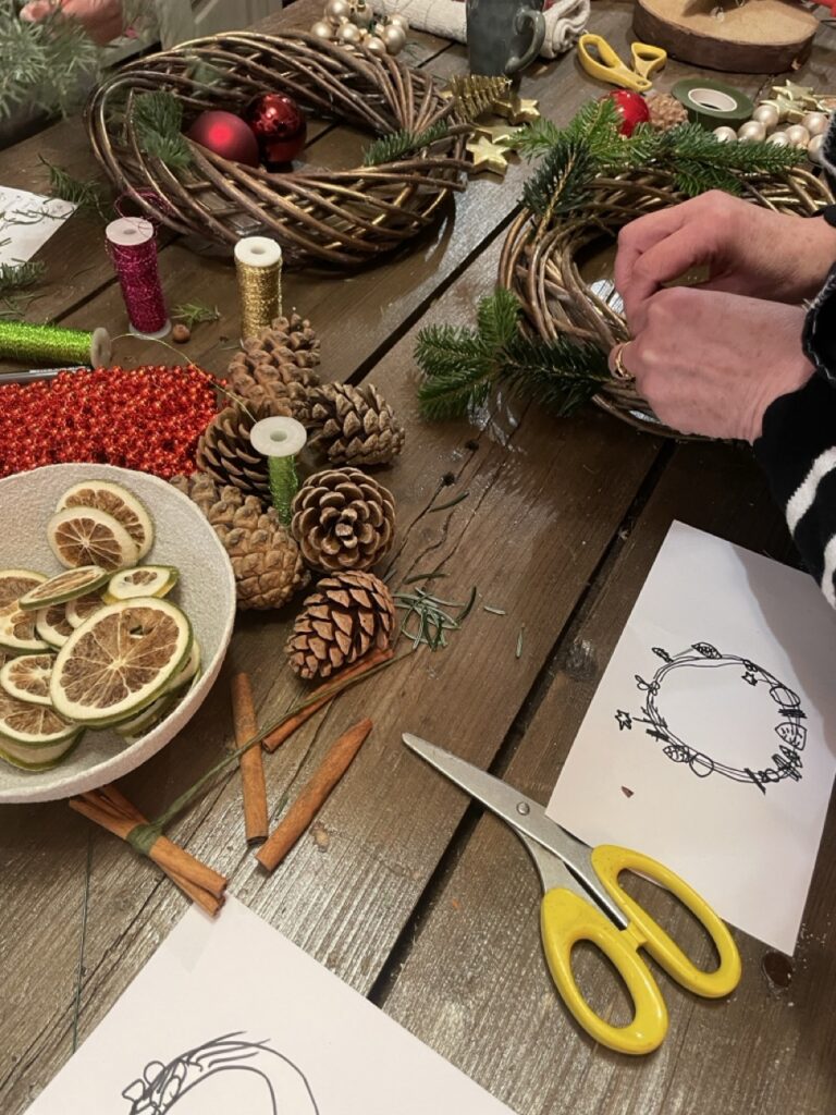 Préparation d'une couronne végétale lors d'un atelier créatif chez Yann-H2o, artisan fleuriste à Paris 11. Branchages, feuillages, pommes de pin, agrumes séchés et végétaux naturels composent une décoration florale de saison.