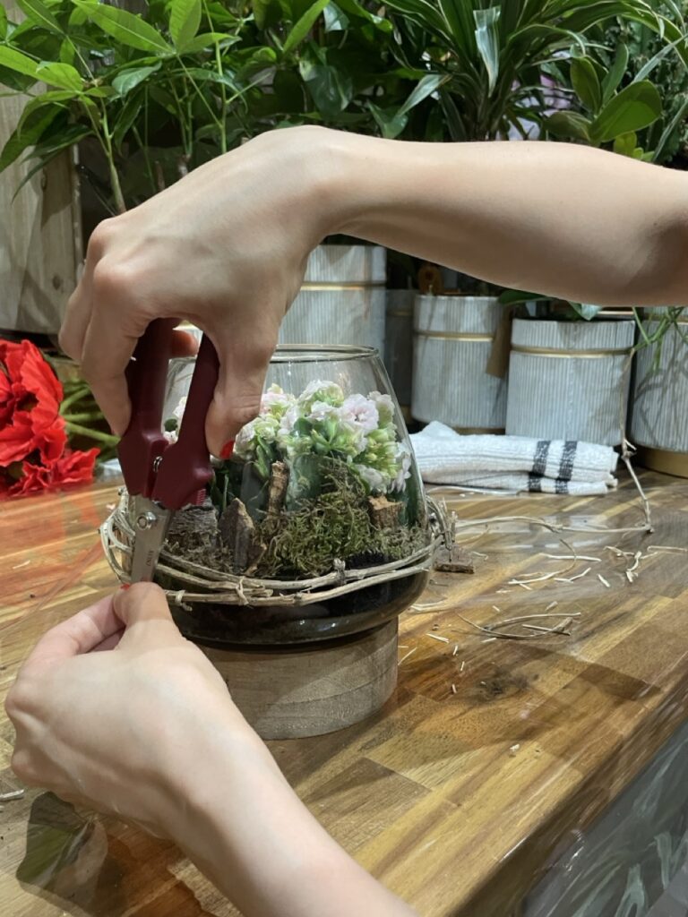 Création d'un terrarium végétal lors d'un atelier floral chez Yann-H2o, artisan fleuriste à Paris 11. Les participants réalisent une composition avec des fleurs de saison et des éléments naturels.