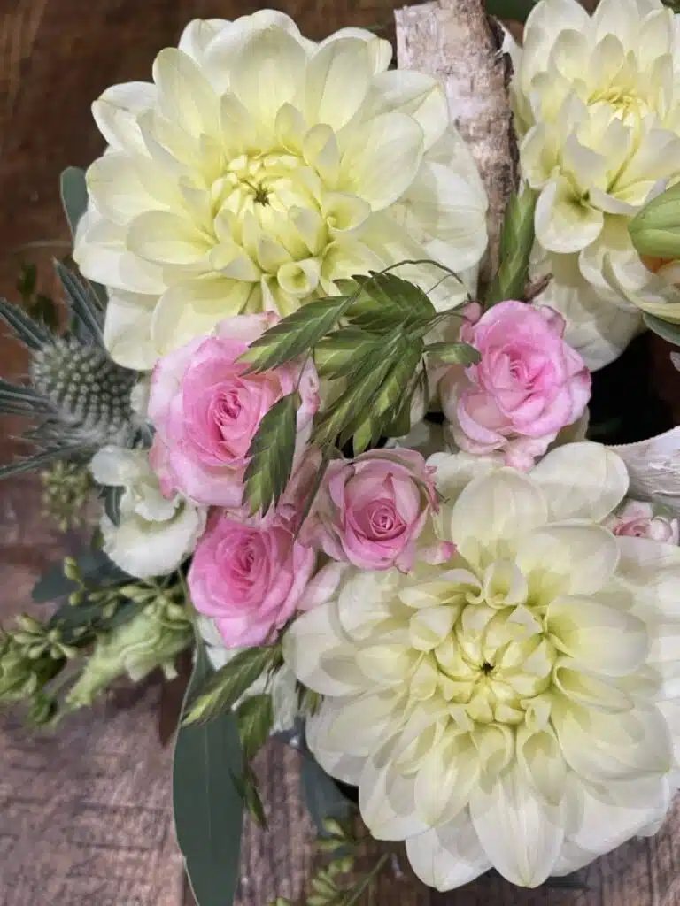 Bouquet de fleurs de saison réunissant des dahlias blancs, des roses roses, une orchidée Phalaenopsis et des feuillages, réalisé par Yann-H2o, artisan fleuriste à Paris 11.