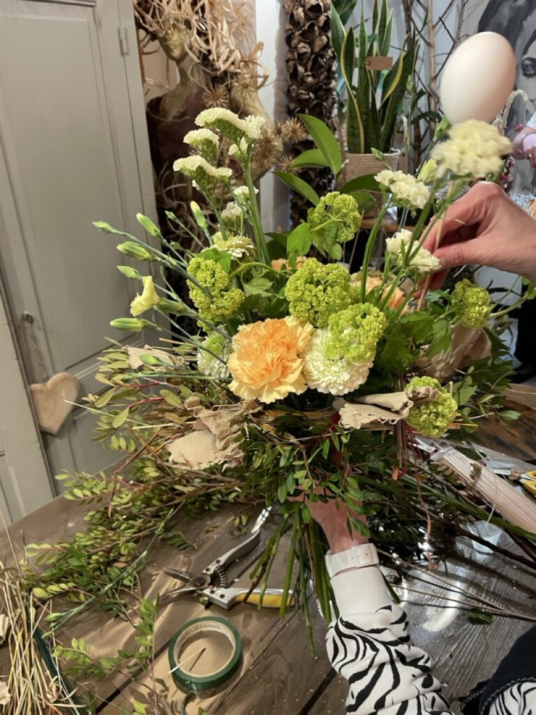 Participant composant un bouquet contemporain avec des fleurs de saison et des végétaux lors d'un atelier de création végétale animé par Yann-H2o, artisan fleuriste à Paris 11.