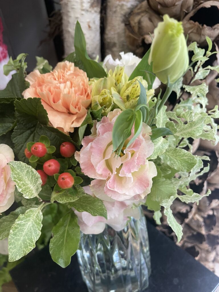 Composition florale raffinée mettant à l'honneur le lisianthus rose, accompagné d'un œillet pêche, d'alstroemeria jaune, de baies d'hypericum et de feuillages décoratifs. Bouquet réalisé à la main par Yann-H2o, artisan fleuriste à Paris 11.