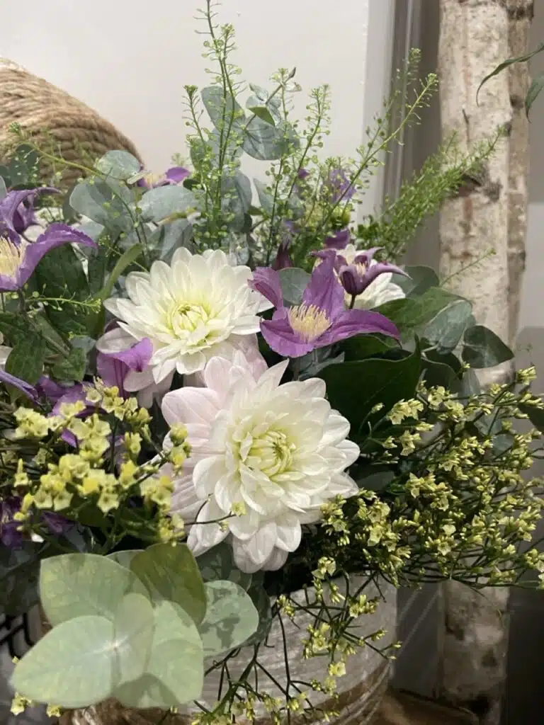 Composition florale mêlant des dahlias blancs, des clématites violettes, de l'eucalyptus et des fleurs de saison, réalisée par Yann-H2o, artisan fleuriste à Paris 11.