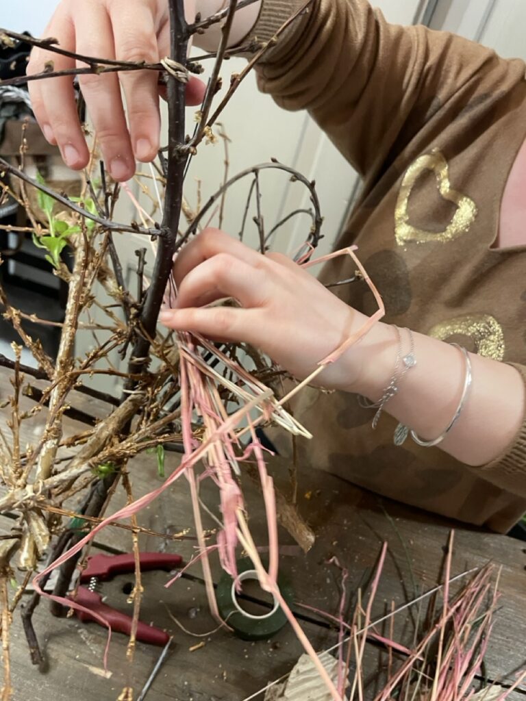 Participant réalisant une création végétale avec des branchages lors d'un atelier convivial animé par Yann-H2o, artisan fleuriste créateur à Paris 11. Les fleurs de saison et les matières naturelles invitent chacun à exprimer sa créativité dans une ambiance chaleureuse.