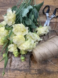 Tiges de lisianthus crème fraîchement sélectionnées sur la table de travail de Yann-H2o, artisan fleuriste à Paris 11. Une fleur de saison élégante, réputée pour sa délicatesse, sa longue tenue en vase et sa place de choix dans les bouquets raffinés.