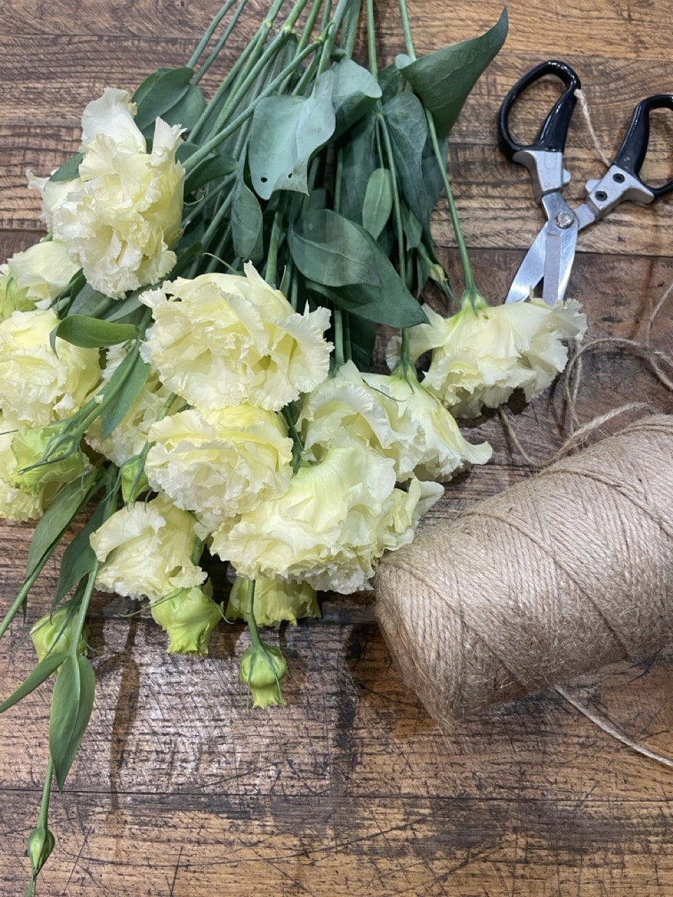 Tiges de lisianthus crème fraîchement sélectionnées sur la table de travail de Yann-H2o, artisan fleuriste à Paris 11. Une fleur de saison élégante, réputée pour sa délicatesse, sa longue tenue en vase et sa place de choix dans les bouquets raffinés.