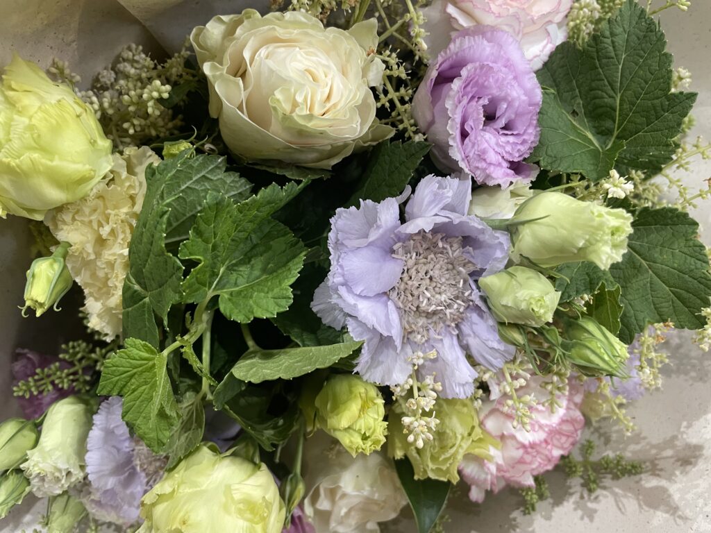 Un bouquet de lisianthus verts, mauves et blancs accompagné de roses et de scabieuses, réalisé par Yann H2O, artisan fleuriste à Paris 11 avec livraison de fleurs dans tout Paris.