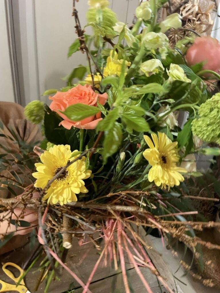 Bouquet structuré d’automne aux roses orangées, gerberas jaunes, fleurs vertes et branchages naturels, réalisé lors d’un atelier floral à Paris 11 chez Yann-H2o.