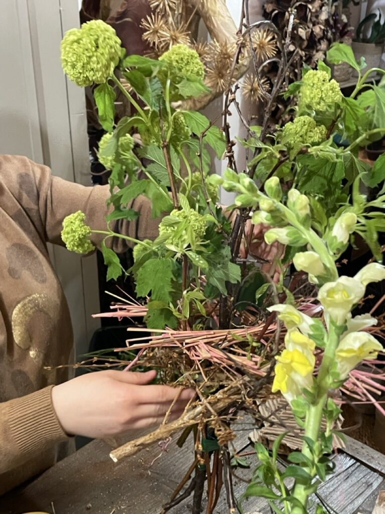 Création d’un bouquet structuré d’automne lors d’un atelier floral à Paris 11 chez Yann-H2o, mêlant fleurs vertes, mufliers jaune pâle et branches naturelles.