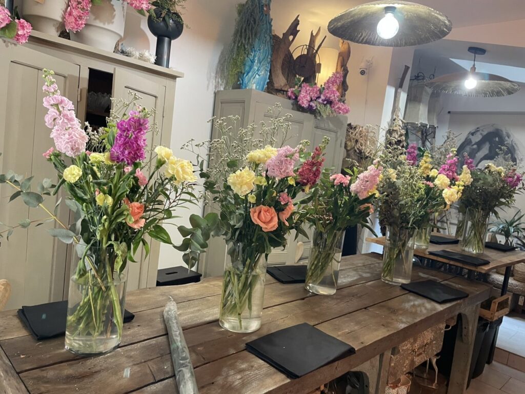 Atelier floral privatisé chez Yann-H2o à Paris 11, avec bouquets de fleurs colorées disposés sur une grande table en bois pour un moment créatif et convivial.