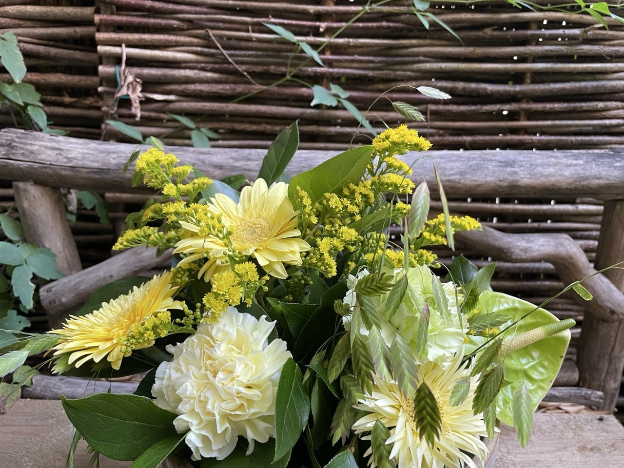 Bouquet champêtre aux gerberas jaune pâle, œillets blancs, anthurium vert et graminées, imaginé par Yann-H2o, fleuriste à Paris 11.