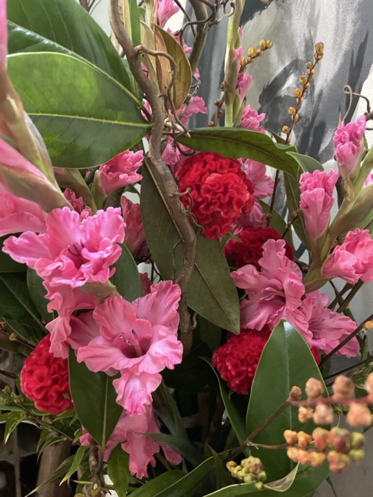 Célosies fuchsia aux fleurs veloutées associées à des glaïeuls roses et des feuillages dans une composition florale chez Yann-H2o, artisan fleuriste à Paris 11.