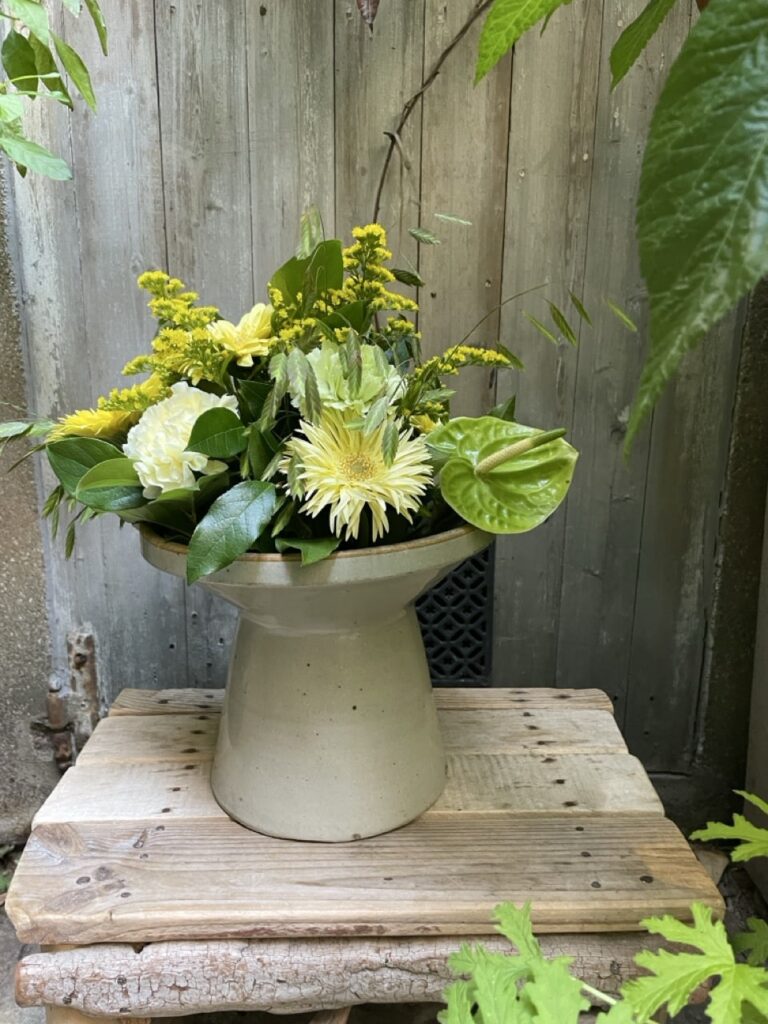Composition florale jaune, blanche et verte dans un vase en céramique, avec gerberas, anthurium et graminées, créée par Yann-H2o à Paris 11.